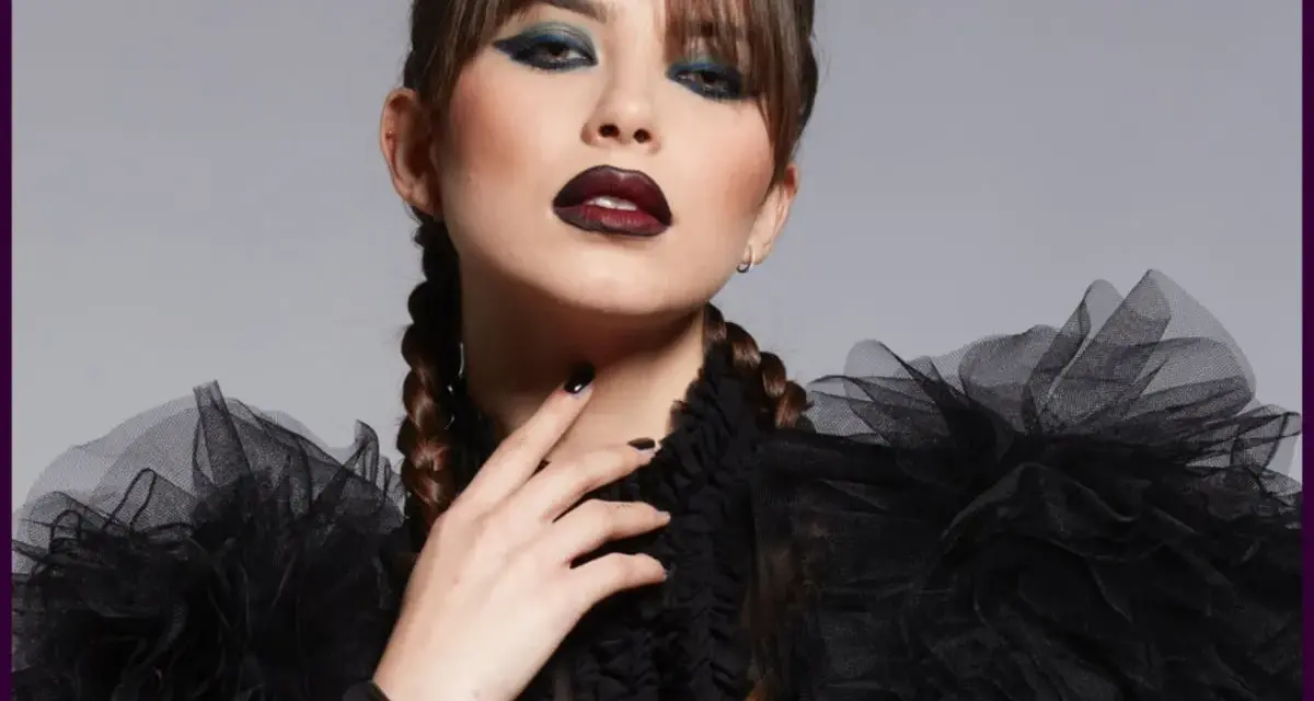 Donna con trucco halloween semplice: labbra scure, occhi smokey blu e trecce. Abito nero con ruches.