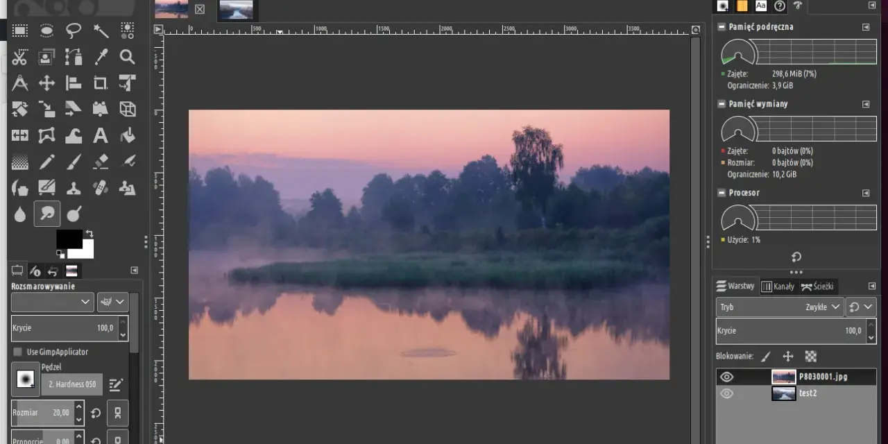 Mglisty poranek nad rzeką, edytowany w **GIMP 2.10**. Widać odbicie drzew w wodzie i wschód słońca.