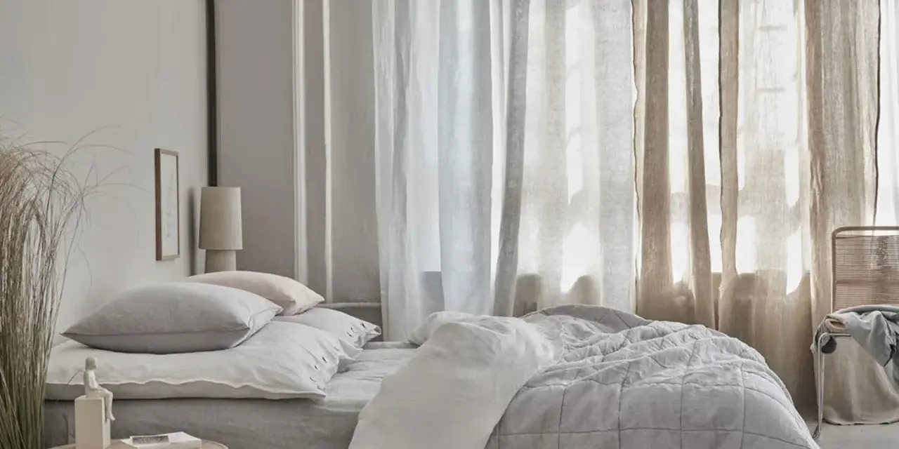 Sanfte Gardinen Ideen für ein Schlafzimmer: Leinenstoffe in Weiß und Beige schaffen eine luftige Atmosphäre über einem gemütlichen Bett.