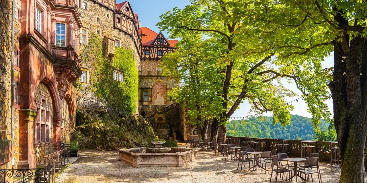 Zamek Książ i okolice: taras z fontanną i stolikami pod drzewami, idealne miejsce na relaks. Warto zobaczyć tę architekturę.