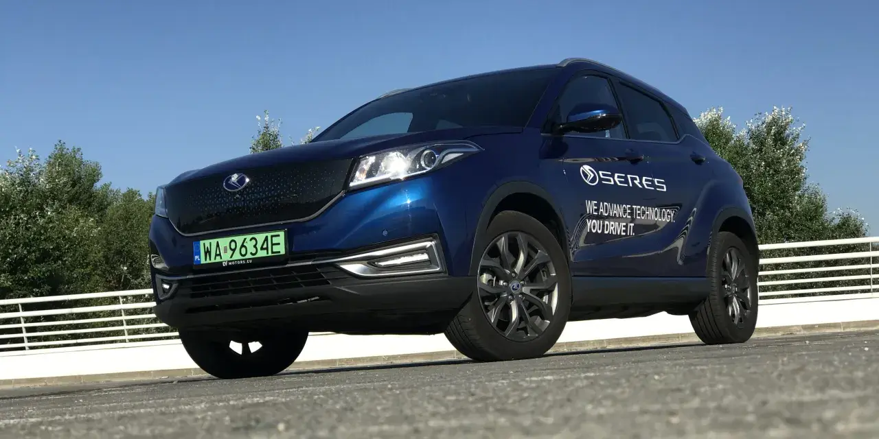 Niebieski SUV Seres 3 zaparkowany na zewnątrz, z widocznym logo i napisem.