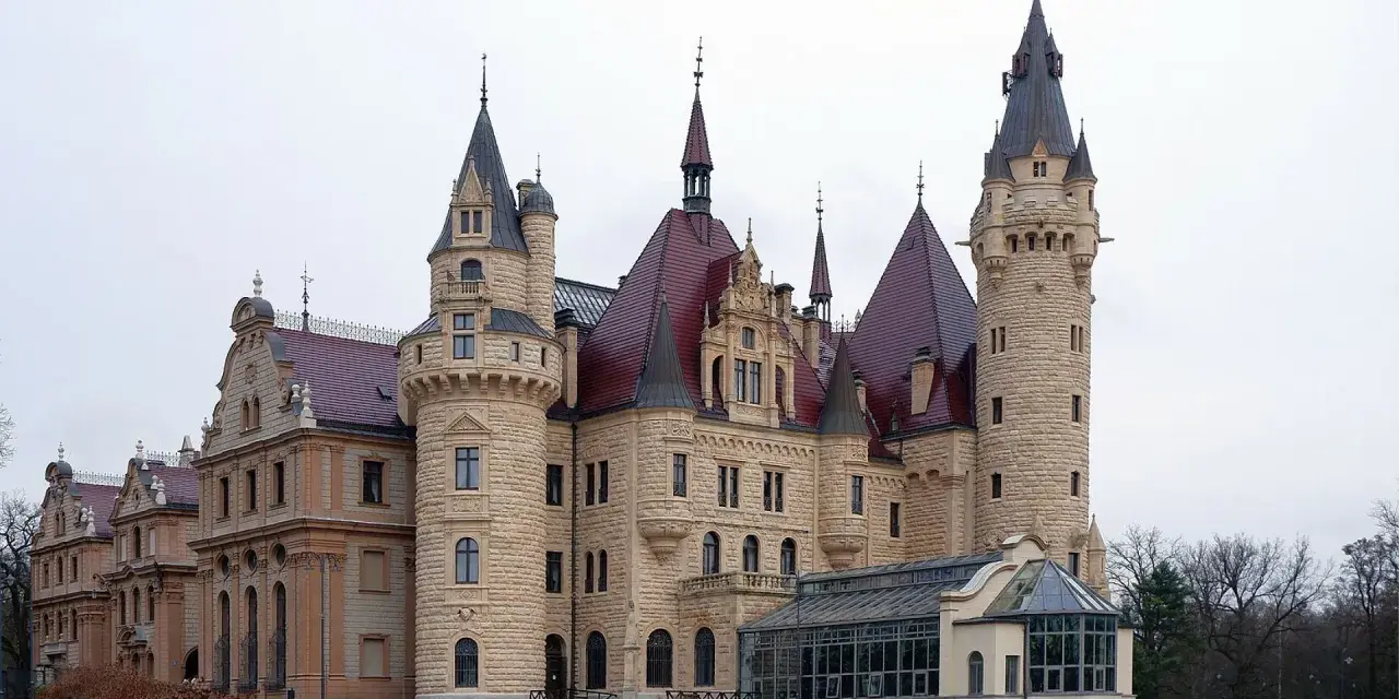 Imponujące pałace w Polsce, jak ten z kamienia i czerwonym dachem, zachwycają wieżami i bogactwem detali architektonicznych.