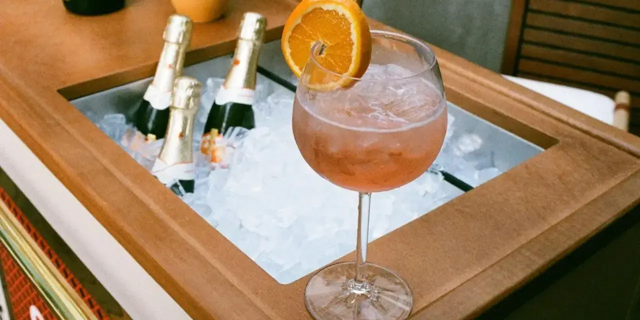 Orzeźwiający Aperol z pomarańczą i butelkami prosecco w lodzie. Idealne na letnie popołudnie.