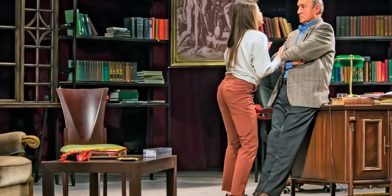 Młoda kobieta rozmawia ze starszym mężczyzną w gabinecie pełnym książek. Scena z przedstawienia "Edukacja Rity".