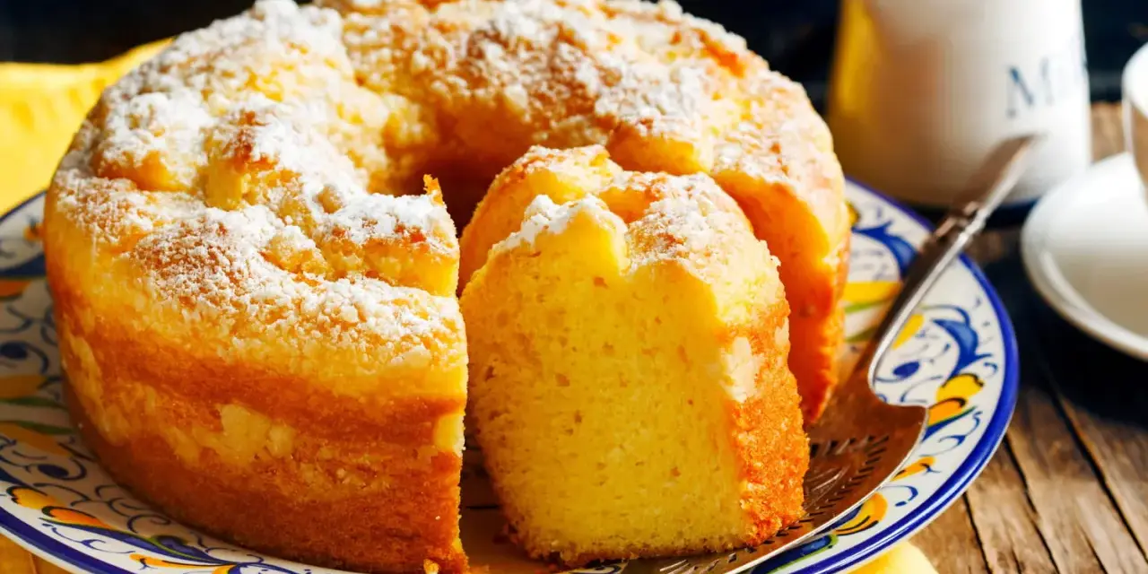 Gâteau sans gluten, saupoudré de sucre glace, sur une assiette décorée. Une part est coupée, prête à être dégustée.