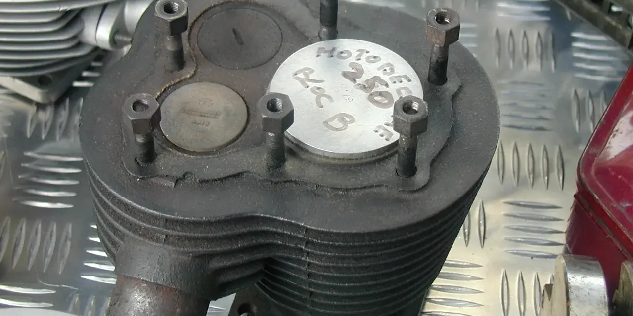Stary silnik dolnozaworowy z widocznymi zaworami i oznaczeniem "Motobecane 250".