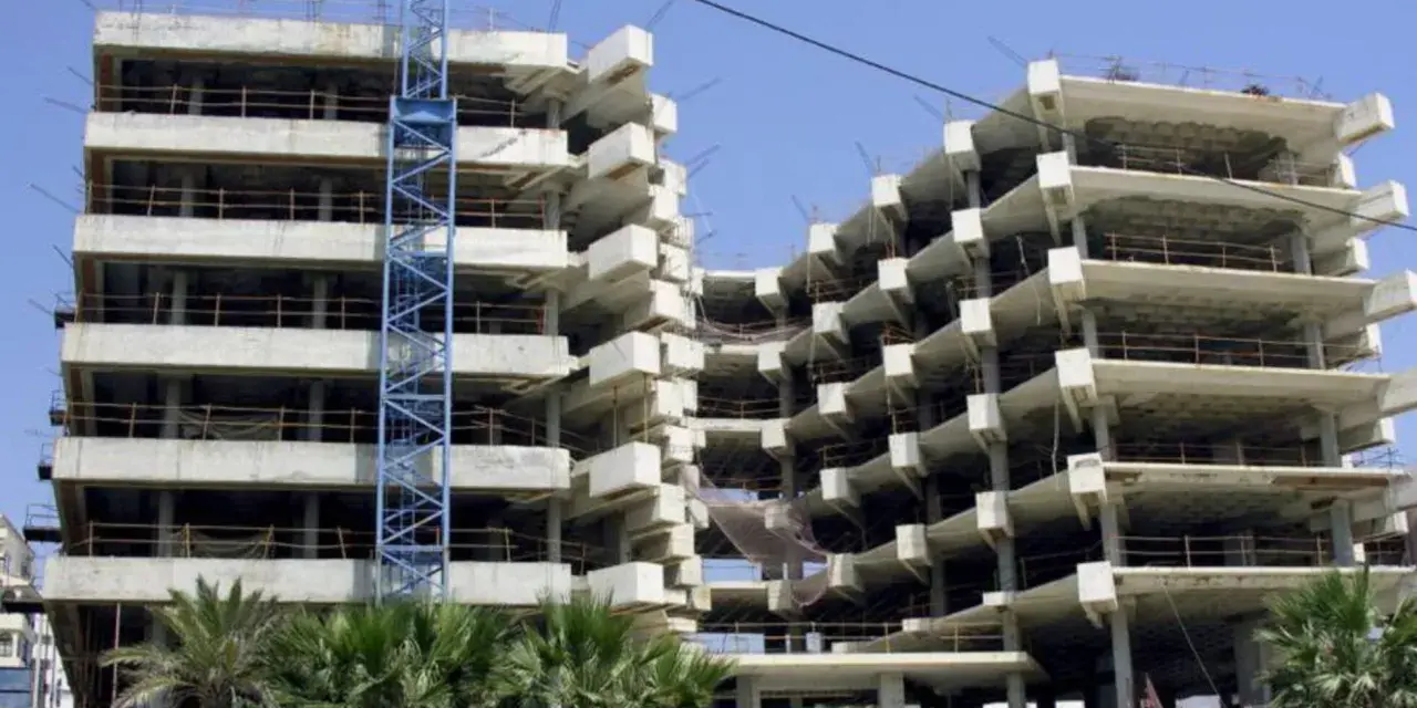 Edificio en construcción con grúa azul. La obra avanza lentamente, generando preocupación por sentencias de retraso en la entrega de vivienda de obra nueva.