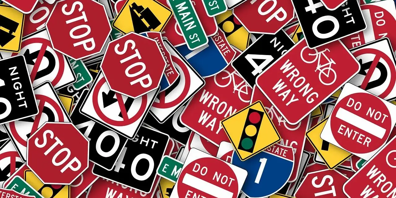 Un groviglio di segnali stradali, tra cui "STOP", "DO NOT ENTER" e "WRONG WAY", che ricordano l'art. 45 del Codice della Strada.