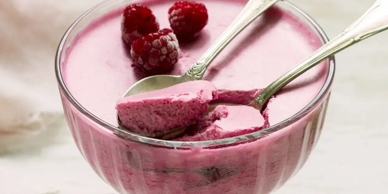 Himbeere-rotweincreme selbstgemacht in einer Glasschale, garniert mit frischen Himbeeren und zwei Löffeln.