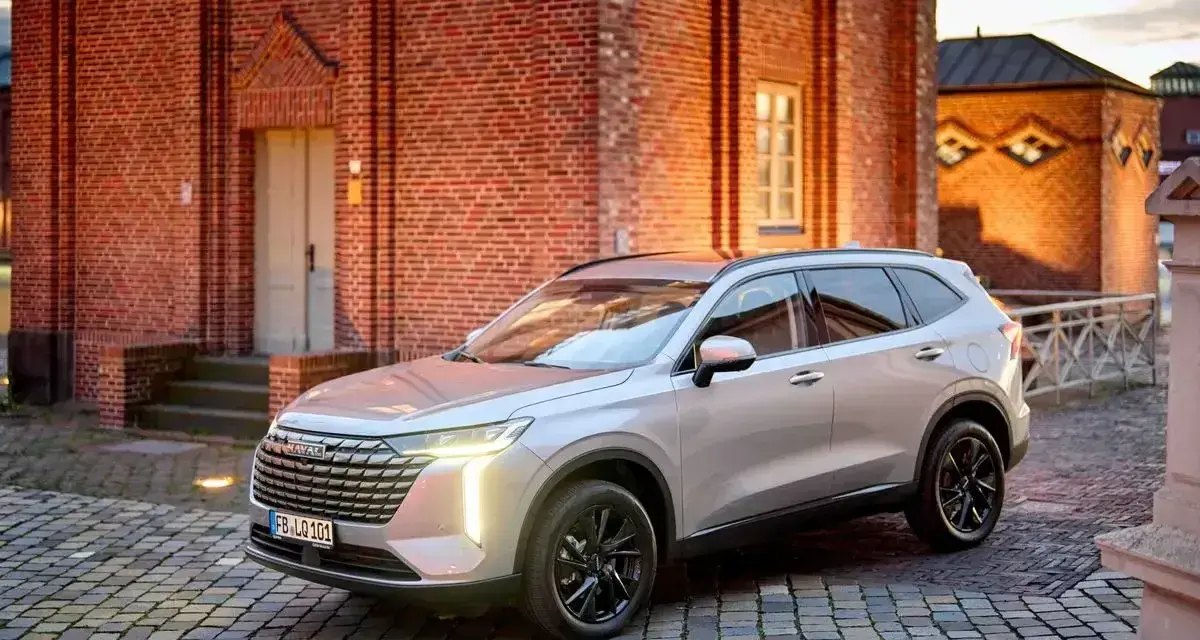 Srebrny Haval SUV zaparkowany na brukowanym dziedzińcu przed ceglanym budynkiem.