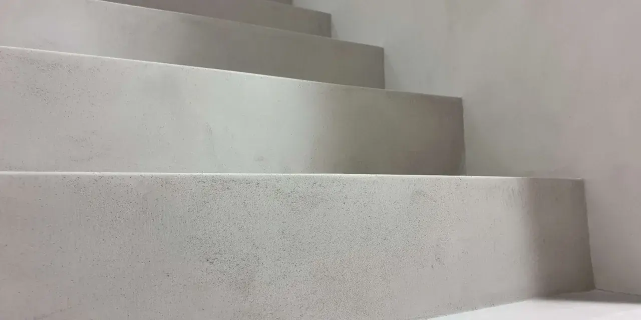 Nowoczesne schody z surowego betonu na klatce schodowej. Minimalistyczny design, jasnoszare stopnie.