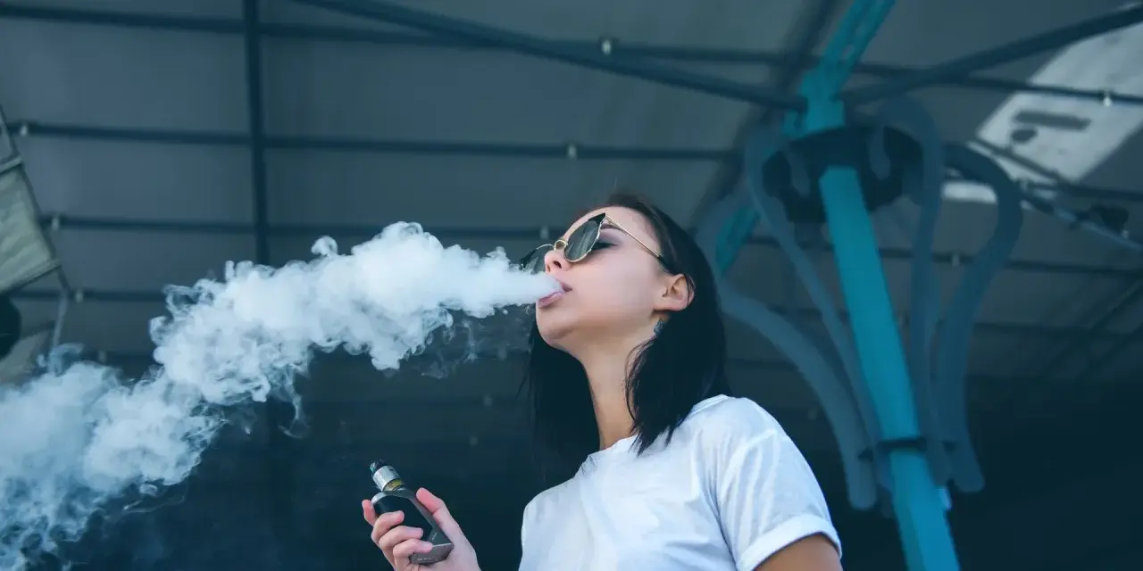 Joven exhala humo de un vaper, una práctica que demuestra que el vaper es malo para la salud.