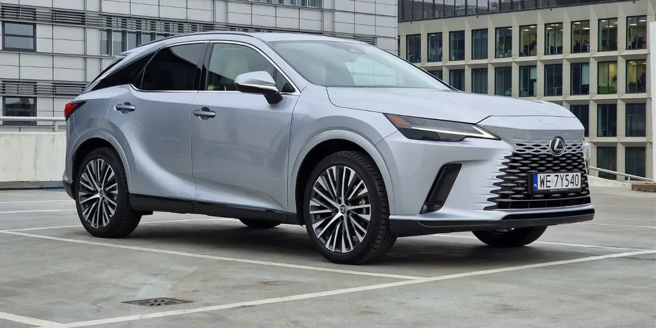 Srebrny Lexus RX 350h zaparkowany przed nowoczesnym budynkiem.