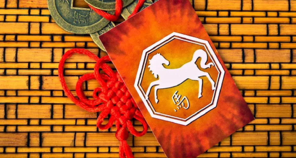 Chiński znak zodiaku 1990 - koń. Obok monety i czerwony sznurek.