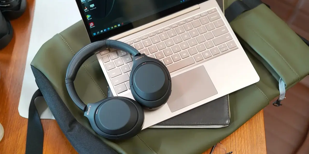 Słuchawki bezprzewodowe Sony leżą na laptopie, gotowe do połączenia. Dowiedz się, jak podłączyć słuchawki bezprzewodowe do laptopa, by cieszyć się dźwiękiem.