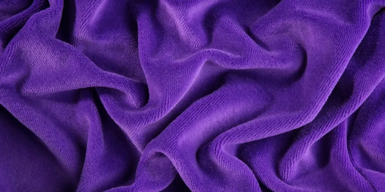 Ondeggiante velour tessuto viola, morbido e invitante, con pieghe profonde che creano un gioco di luci e ombre.