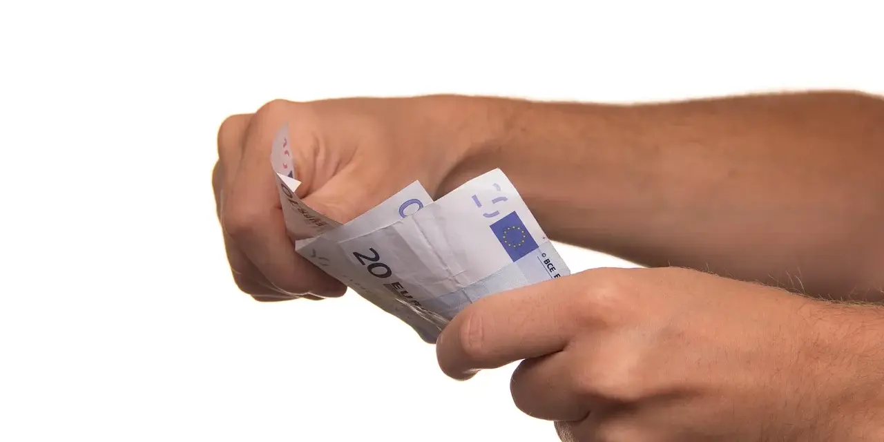 Dłonie trzymają banknoty euro. To może być symboliczne zawiadomienie o uchyleniu zajęcia, gdy pieniądze wracają do właściciela.