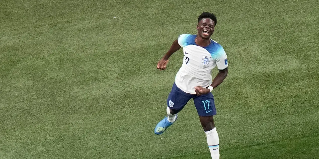 Bukayo Saka celebra un gol con euforia en el campo de fútbol.