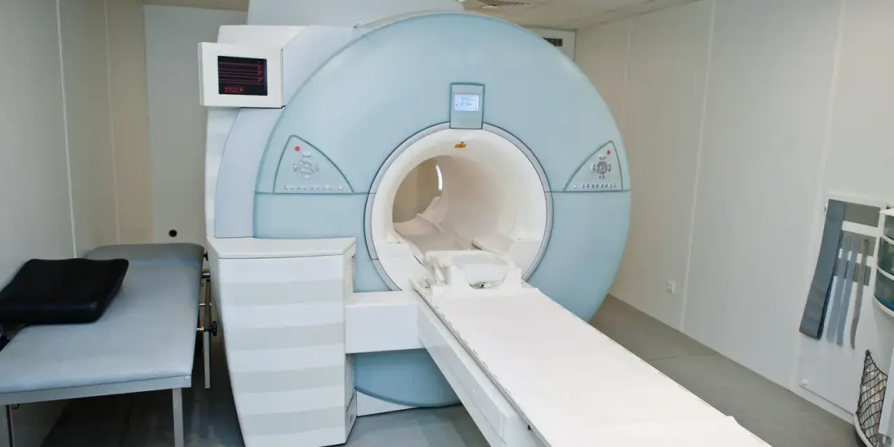 Nowoczesny aparat rezonansu magnetycznego (MRI) w gabinecie lekarskim z kozetką.