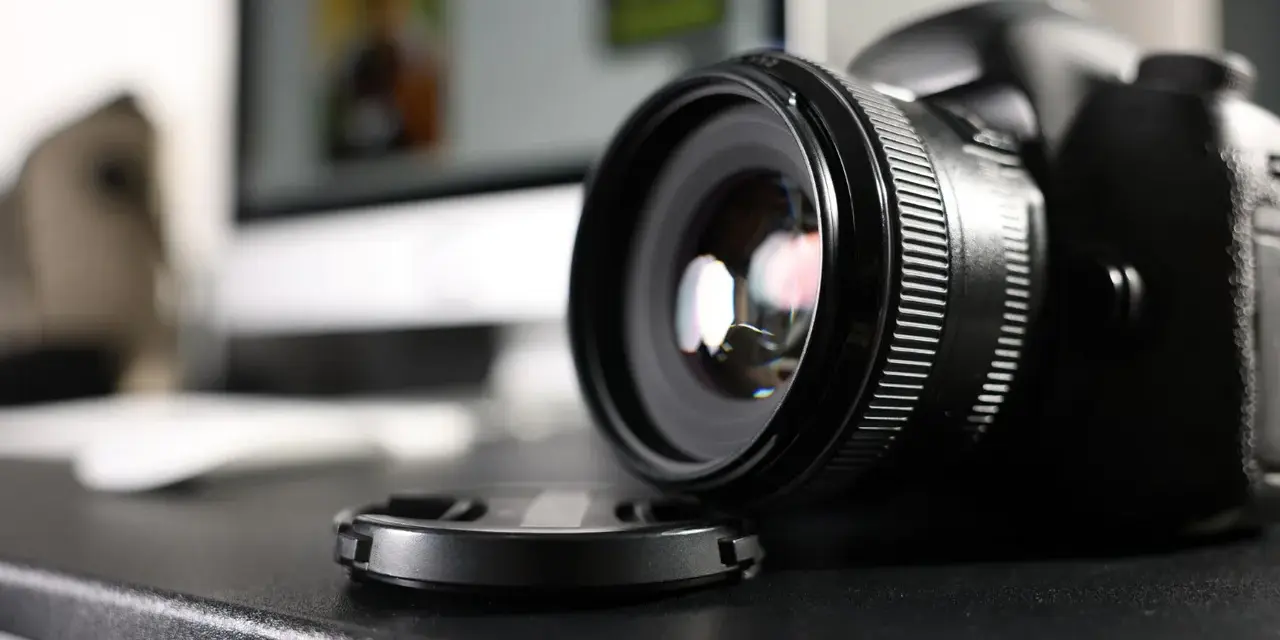 Czarne body lustrzanki cyfrowej z obiektywem i dekielkiem na czarnym blacie. Zastanawiasz się dslr co to? To właśnie to!