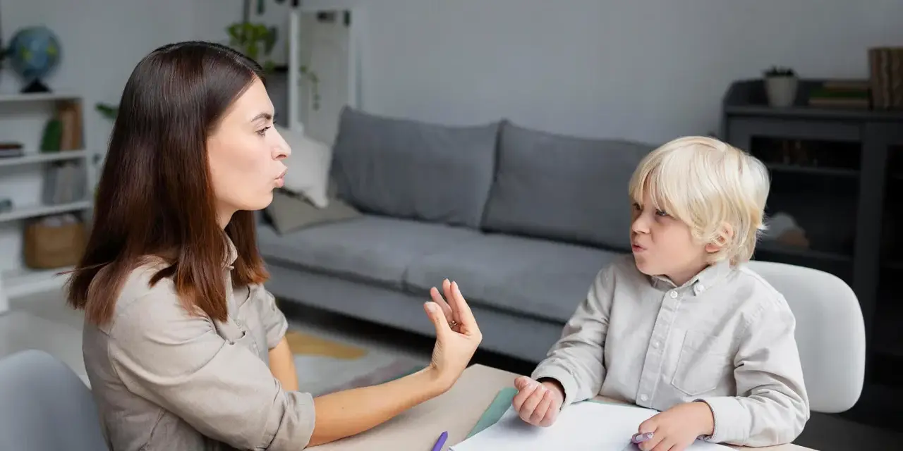 Terapeuta pracuje z dzieckiem, które ma orzeczenie o specjalnych potrzebach edukacyjnych, ćwicząc wymowę.