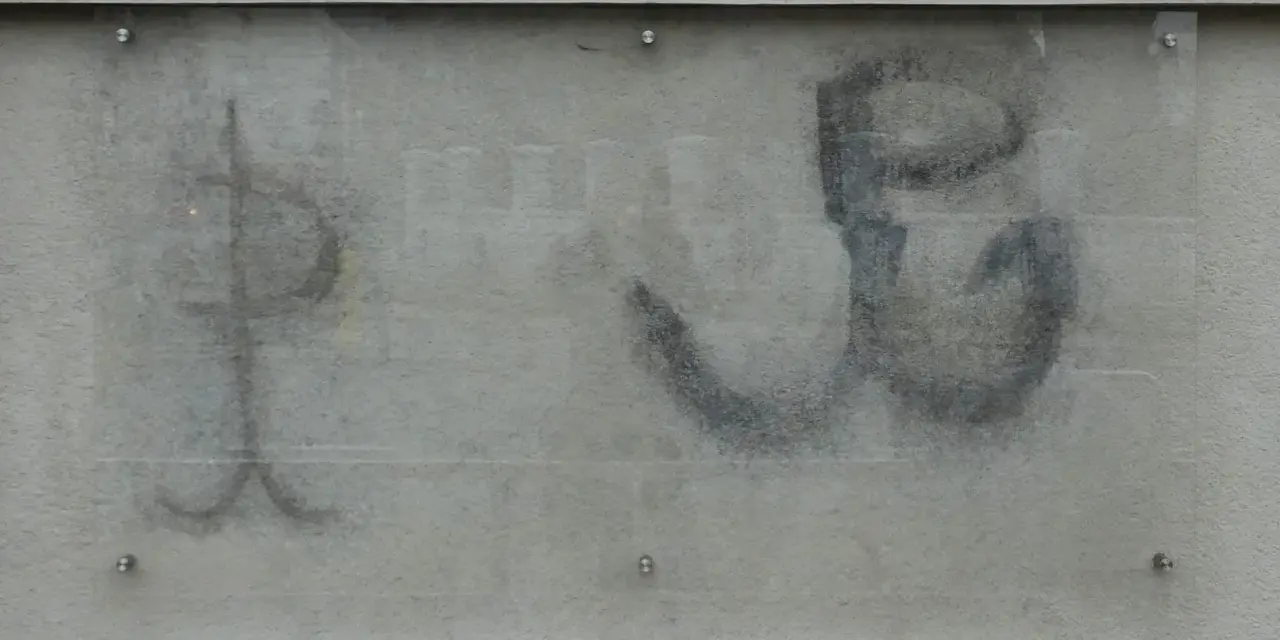 Na szarej ścianie widoczny jest symbol kotwicy, znak Polski Walczącej, namalowany czarną farbą.