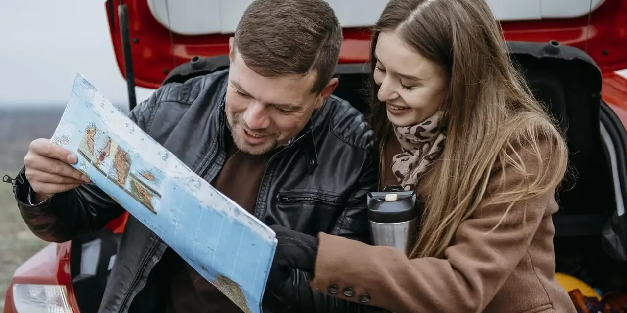 Para planować podróż i ubezpieczenie samochodu na wyjazd za granicę, para przegląda mapę.
