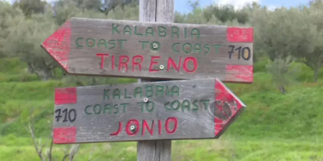 Cartelli in legno indicano il percorso "Kalabria Coast to Coast": uno punta a Tirreno, l'altro a Jonio.