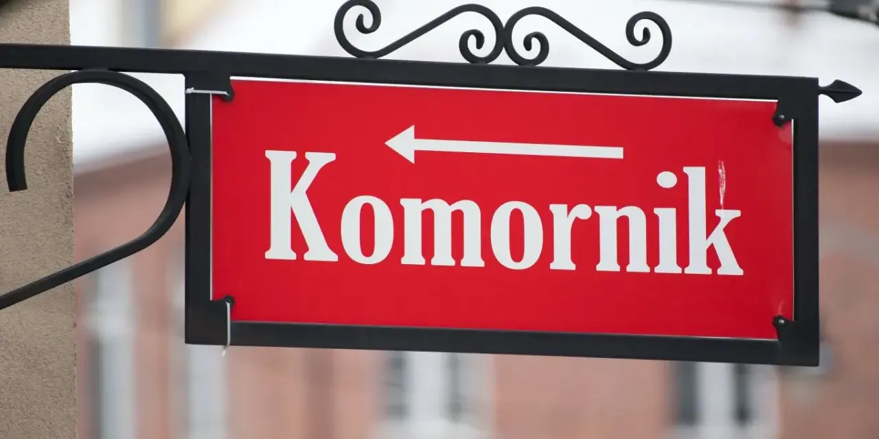 Czerwona tabliczka z napisem "Komornik" i strzałką w lewo. Pamiętaj, czego nie może zabrać komornik z mieszkania!