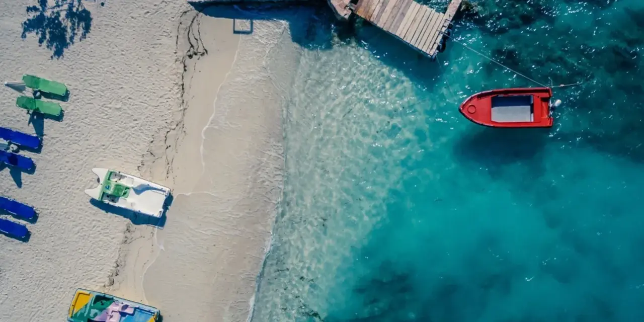 Idealne miejsce, gdzie w styczniu na wakacje: pusta plaża z łódkami i turkusowa woda.