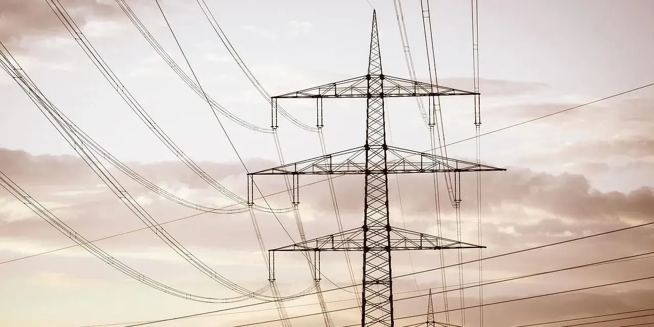 Linie energetyczne mwh przecinają niebo, tworząc geometryczny wzór na tle chmur.