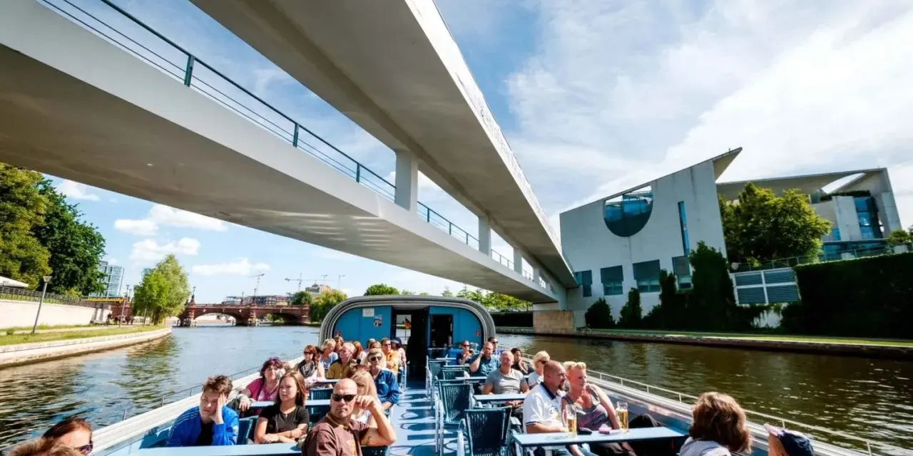 Bootsfahrt auf der Spree in Berlin unter einer modernen Brücke mit Blick auf das Regierungsviertel.