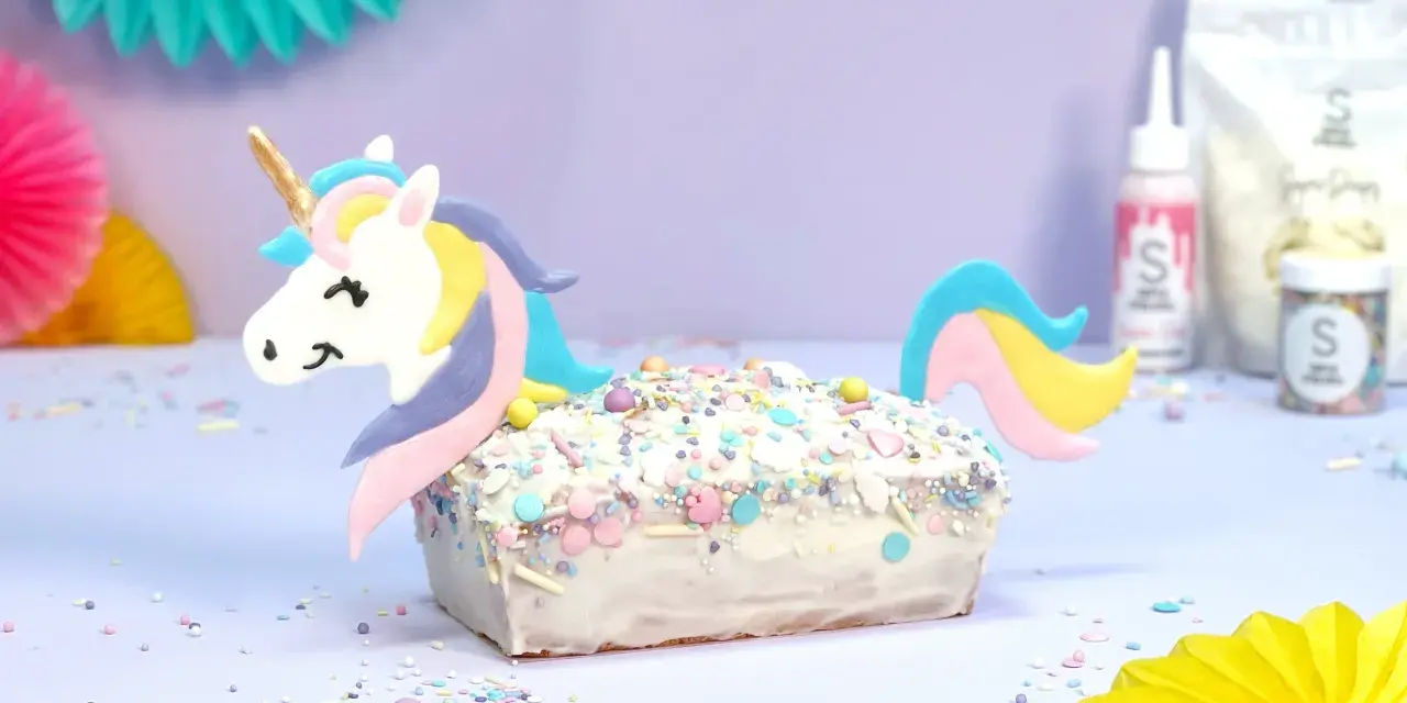 Ein magischer einhorn kuchen, verziert mit bunten Streuseln und einem süßen Einhorn-Topper, bereit für eine märchenhafte Feier.
