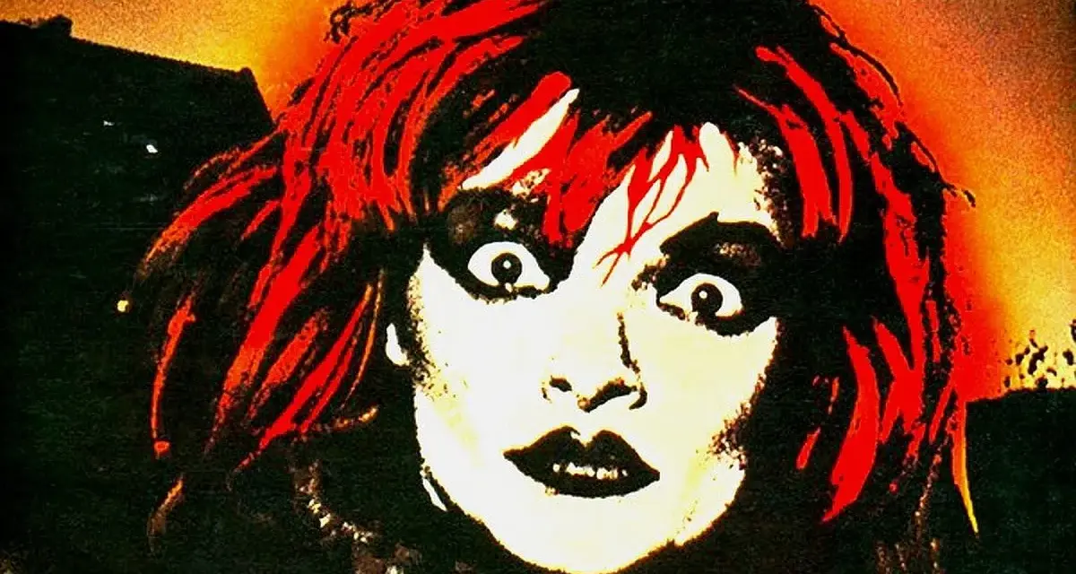 Visage intense d'une femme aux cheveux rouges et maquillage prononcé, évoquant l'esthétique d'un groupe allemand des années 90.
