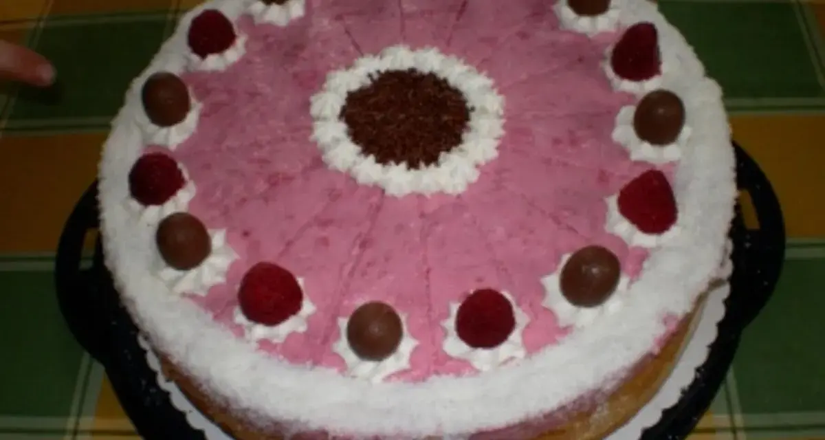 Eine köstliche Kokos Himbeer Torte, verziert mit Schokolade und frischen Himbeeren, bereit zum Genießen.