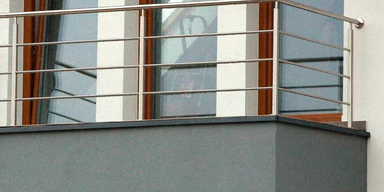 Nowoczesne mocowanie balustrady od czoła balkonu, wykonane ze stali nierdzewnej, z widocznymi czterema poziomymi prętami.