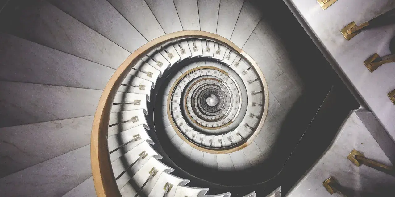 Kręcone schody z marmuru i drewna, tworzące spiralę przypominającą ciąg Fibonacciego w architekturze.