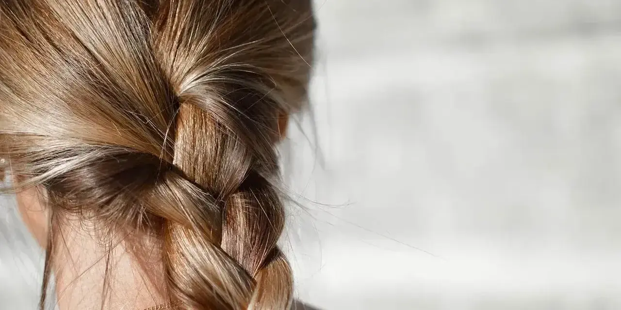 Gładki warkocz z blond włosów, idealny przykład, jak zmniejszyć porowatość włosów.