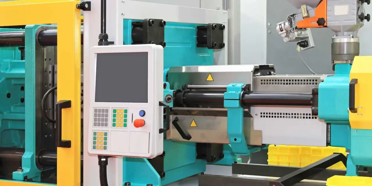 A modern low volume plastic injection molding machine with a control panel and yellow safety guards.