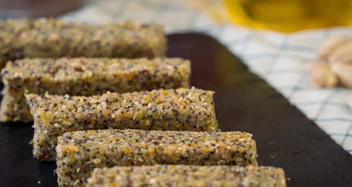 Barritas energéticas caseras de cereales y semillas en una tabla de pizarra.