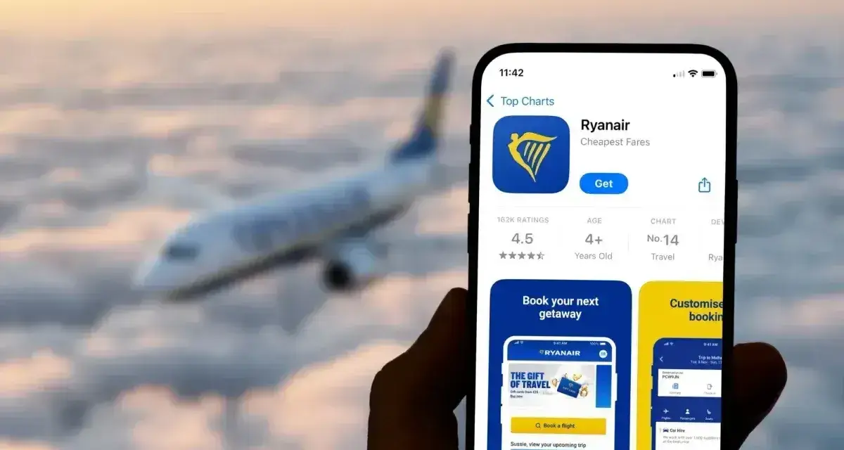 Ręka trzyma smartfon z aplikacją Ryanair, gotową do rezerwacji lotu. W tle widać samolot lecący wśród chmur.