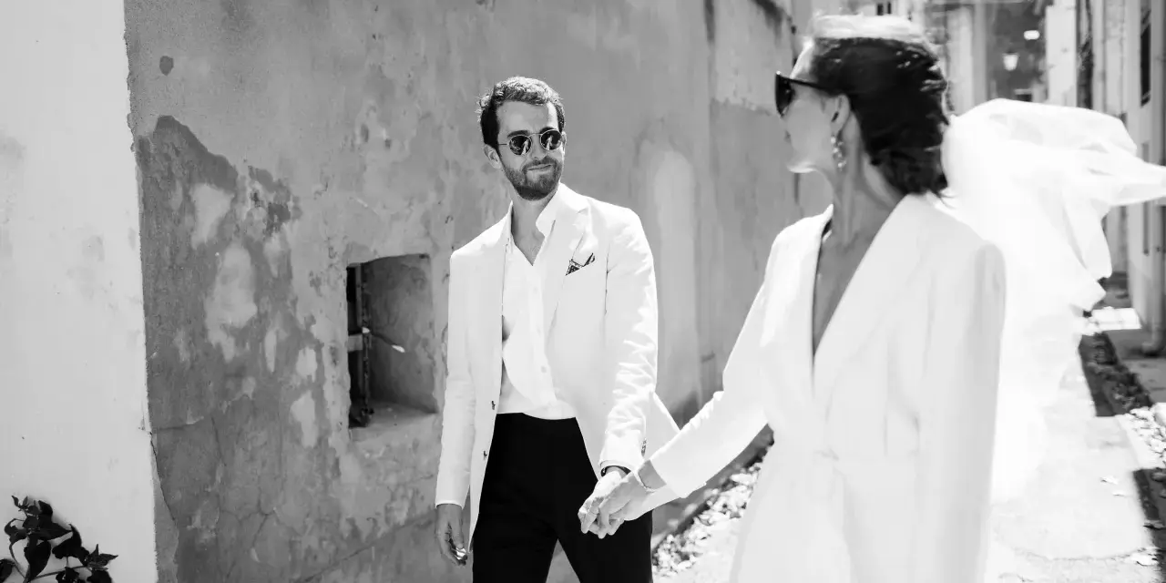 Un couple marié, main dans la main, traverse une ruelle. Ils pensent déjà aux démarches administratives après mariage au service public.