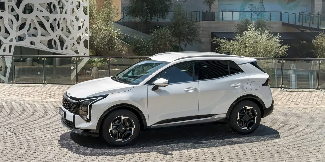 Biała Kia Sportage hybryda na tle nowoczesnej architektury. Stylowy SUV gotowy na miejskie wyzwania.