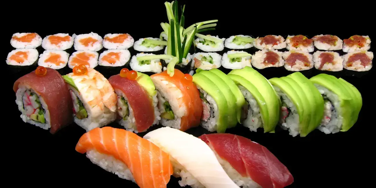 Różnorodne sushi: nigiri z łososiem, tuńczykiem i białą rybą, rolki z awokado, krewetką, tuńczykiem i ogórkiem. Idealne na początek nauki, jak jeść sushi.