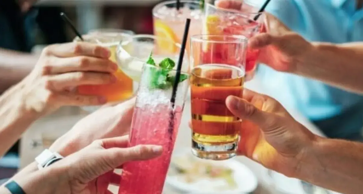 Ludzie wznoszą toasty kolorowymi drinkami. Zastanawiasz się, ile alkoholu można wziąć do Norwegii?