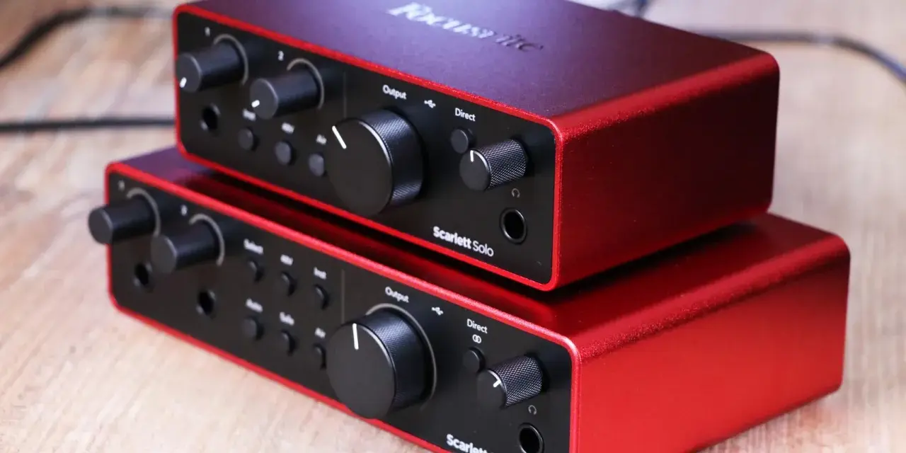 Dwa czerwone interfejsy audio Focusrite Scarlett Solo 3gen i Scarlett 2i2 ułożone jeden na drugim.