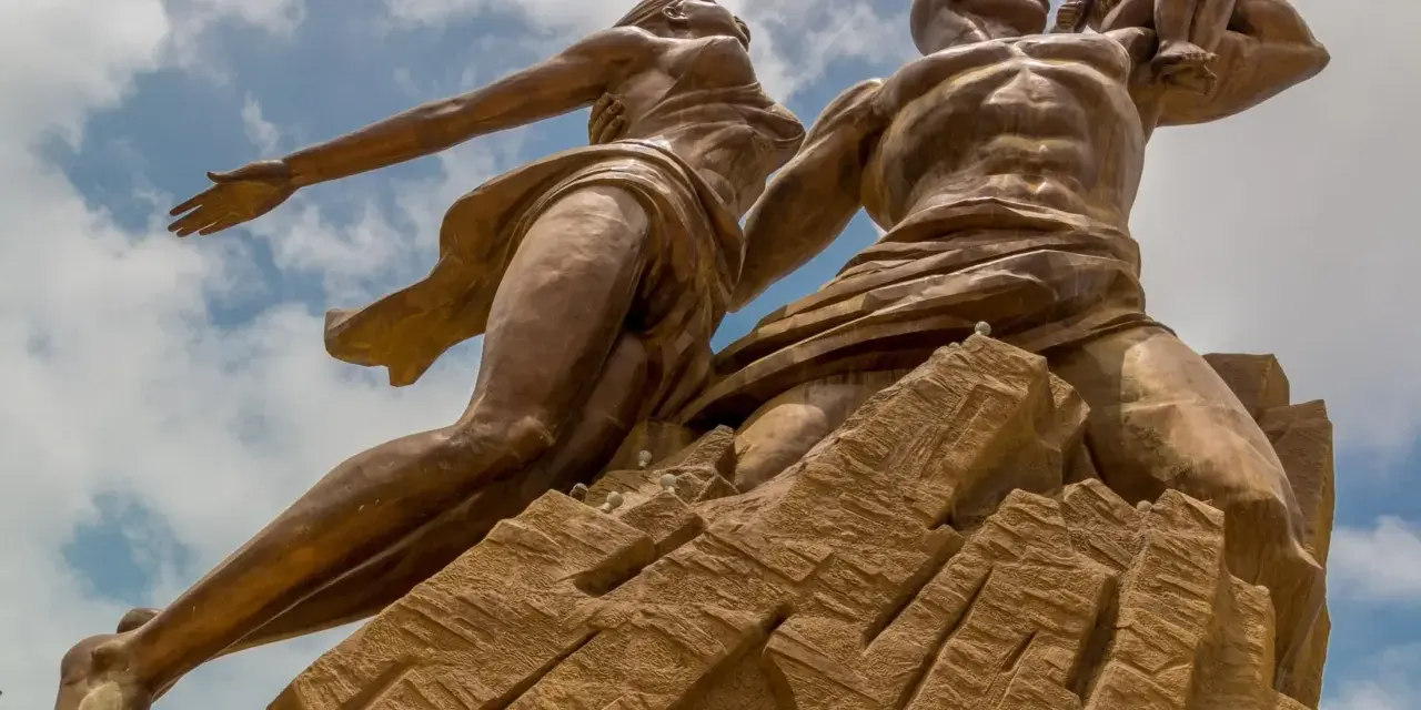 Pomnik Odrodzenia w Senegalu, symbolizujący dumę i przyszłość. Monumentalna rzeźba na tle błękitnego nieba.