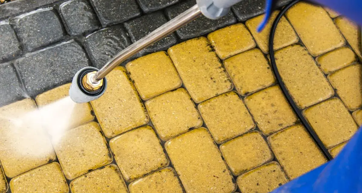 Mycie kostki brukowej myjką ciśnieniową. Woda pod ciśnieniem skutecznie usuwa brud, pokazując, czym wyczyścić kostkę brukową.