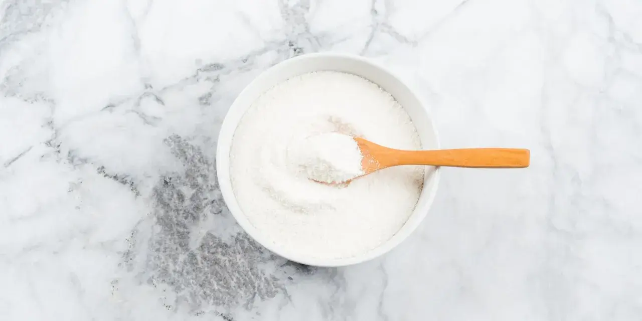 Schüssel mit weißem Pulver, das Kollagenpeptide enthält. Die Wirkung von Kollagenpeptiden ist vielfältig.