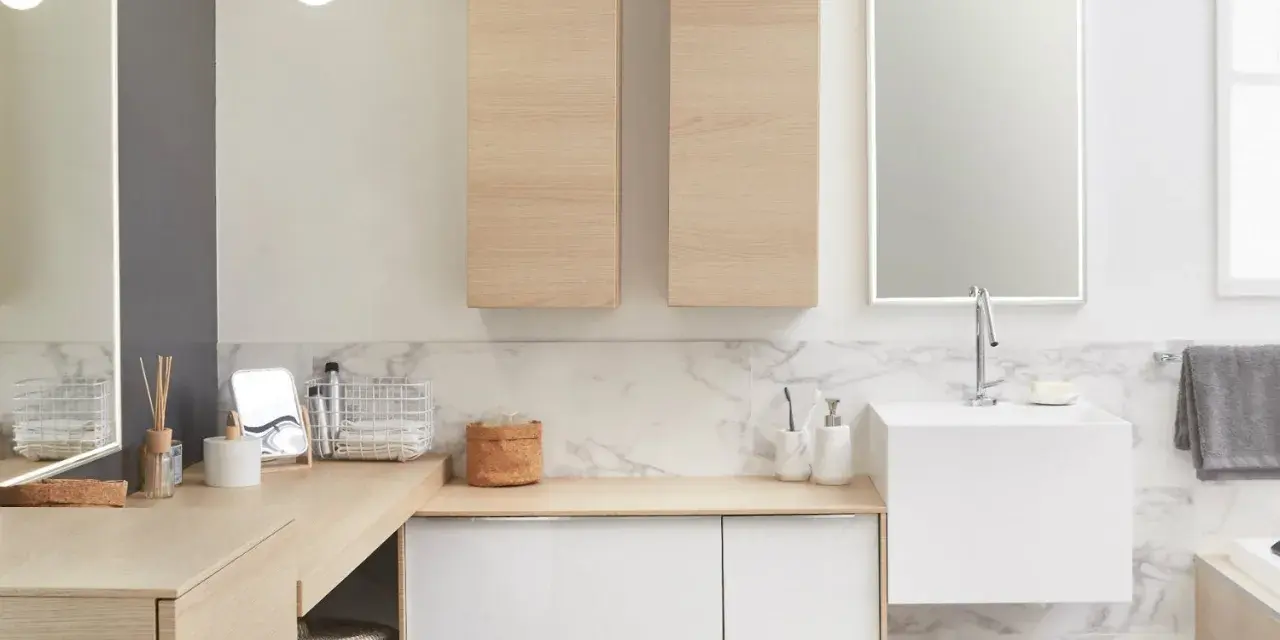 Salle de bain moderne avec un lavabo évier suspendu, des meubles en bois clair et un grand miroir éclairé.